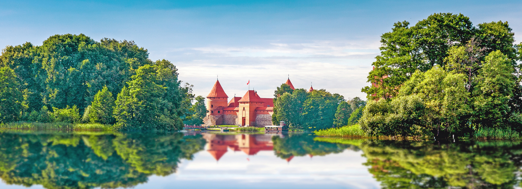Die imposante Wasserburg Trakai in Litauen liegt malerisch auf einer Insel im Galvė-See und spiegelt sich im ruhigen Wasser wider, umgeben von dichten Wäldern.