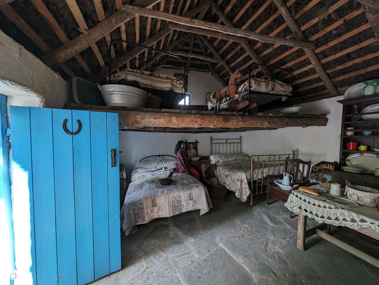 Ein Einblick in vergangene Zeiten wird hier im Inneren eines originalgetreuen Cottages im Kerry Bog Village Museum in Irland gewährt. Die einfache Einrichtung mit Eisenbetten und einem Schlafboden unter dem offenen Dachgebälk vermittelt einen authentischen Eindruck vom kargen Landleben im 19. Jahrhundert.