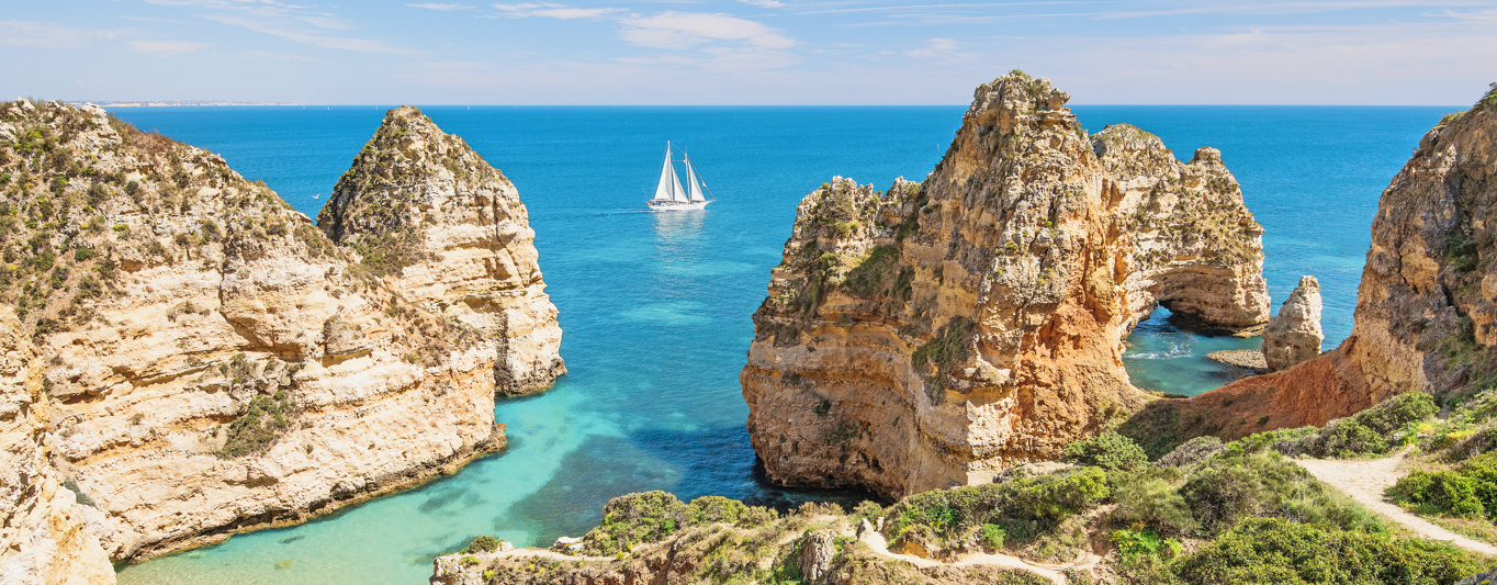 Das Bild zeigt zerklüftete Felsen und blaues Meer in Portugal. Der Ort heißt Ponta da Piedade und dieser liegt direkt am Atlantik. Es ist ein richtiges Highlight in einem Portugal Urlaub.