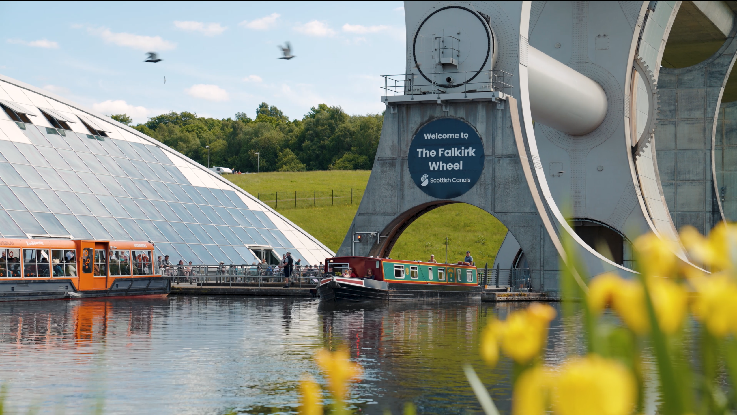 Das beeindruckende Schiffshebewerk Falkirk Wheel in Schottland, wo an einem sonnigen Tag Ausflugsboote im Wasserbecken liegen und diese technische Meisterleistung als einzigartige Sehenswürdigkeit zu einer unvergesslichen Reise und einem erlebnisreichen Urlaub einlädt.
