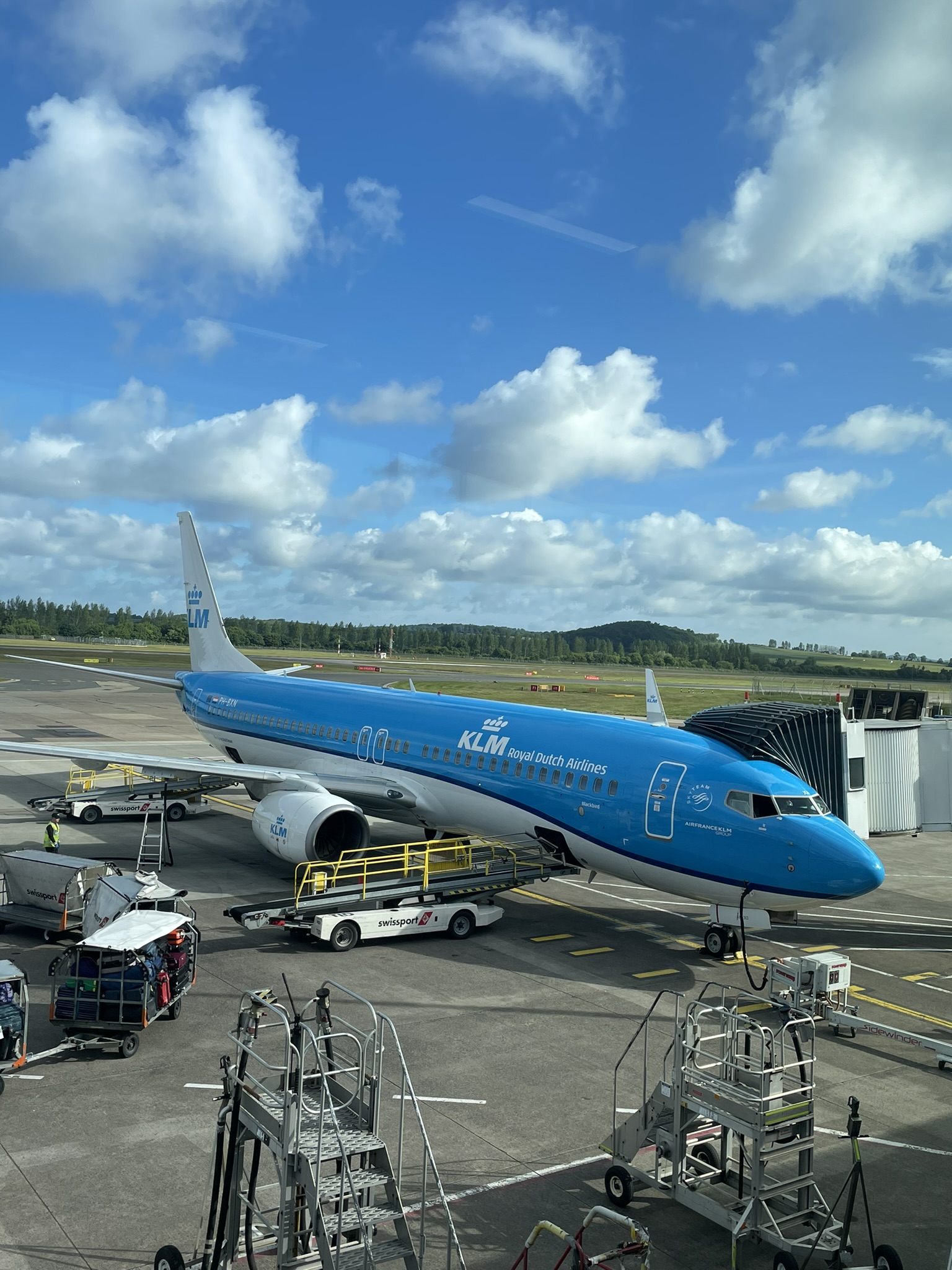 Ein blaues Passagierflugzeug der KLM Royal Dutch Airlines steht an einem Gate am Flughafen und wird für den Abflug oder nach der Ankunft abgefertigt, was den Startpunkt für eine neue Urlaubs-Reise oder ein Abenteuer markiert.