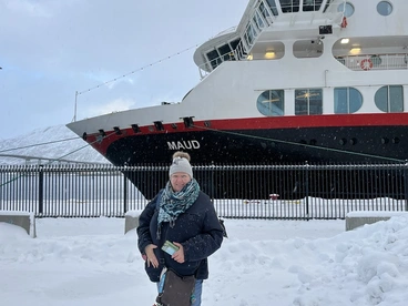 Winterliche Schiffsreise in Tromsø – Erlebnis am Hafen von Nordnorwegen Eine Reisende steht warm eingepackt im Schnee vor einem Schiff im Hafen von Tromsø in Nordnorwegen. Das winterliche Licht und die verschneite Umgebung vermitteln das besondere Flair einer Schiffsreise über die Fjorde des Nordens – ein unvergessliches Erlebnis für Polar- und Norwegenliebhaber.
