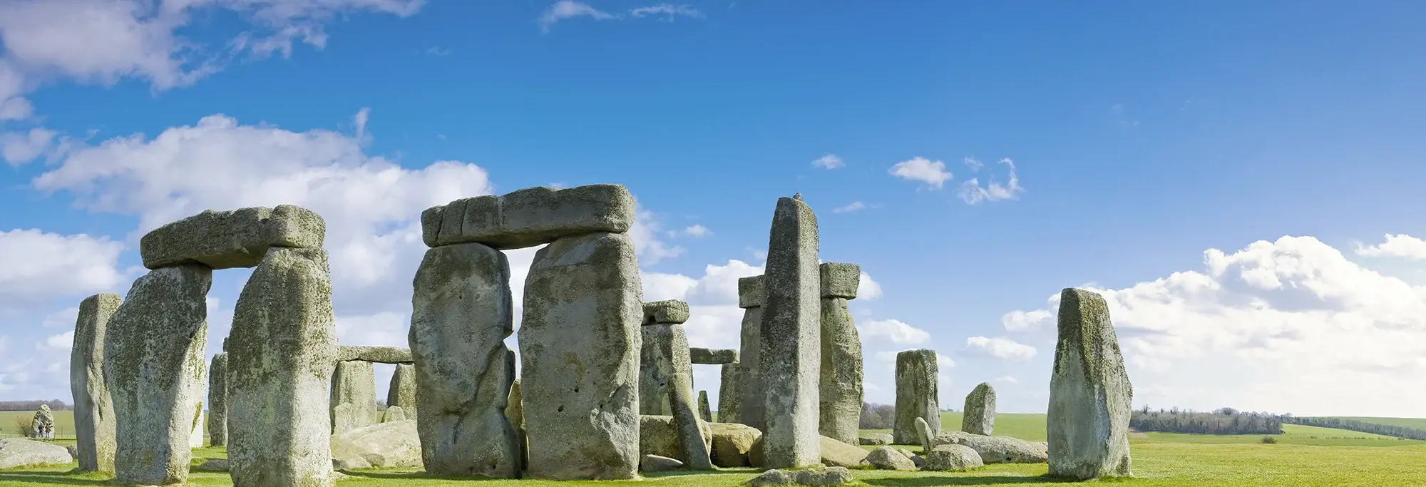 Das weltberühmte Monument Stonehenge in Südengland mit seinen mächtigen Steinkreisen, umgeben von grünen Wiesen und blauem Himmel, gilt als eines der bedeutendsten prähistorischen Bauwerke Europas.